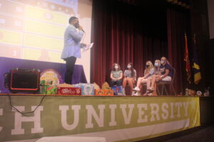Students sit on a stage and answer questions from Black host.