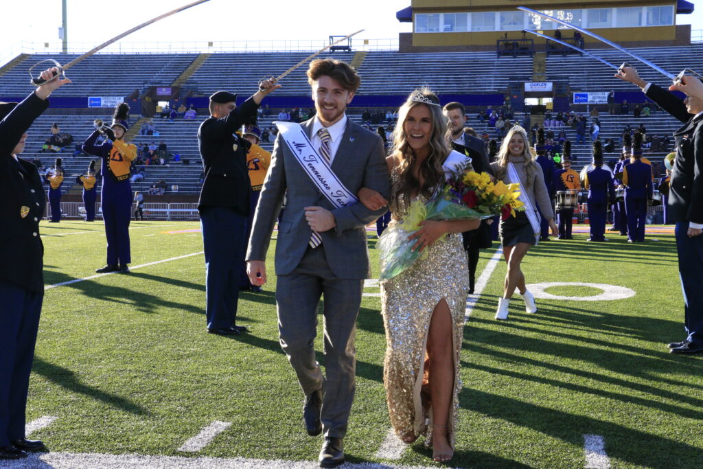 Mr. and Miss Tennessee Tech walk arm-in-arm across Tech's football field.