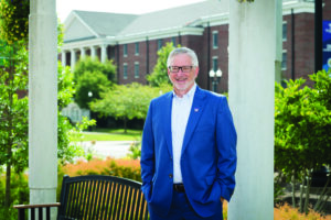 Tech President Phil Oldham poses for a picture outside on a sunny, summer day.